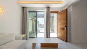 Une pièce moderne avec un canapé blanc, une table en bois et une porte en verre donnant sur un espace extérieur.