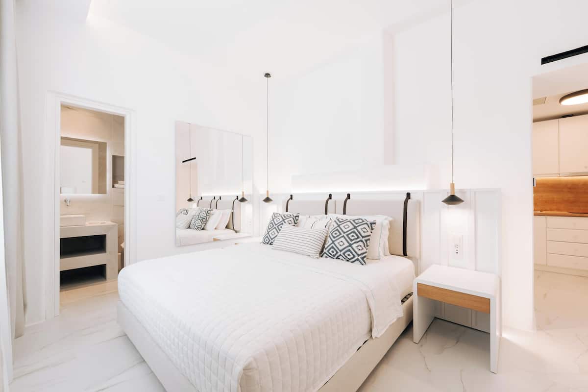 Un dormitorio moderno con una cama grande, mesitas de noche, un espejo y un armario empotrado.