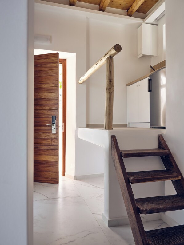 Interior moderno com porta de madeira, escada com corrimão de madeira e parede branca com armário embutido.