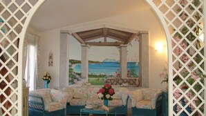 Ett mysigt vardagsrum med utsikt över havet, ett träpanelat tak och möbler med blommönster.