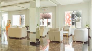 A spacious lobby with a polished marble floor, multiple seating areas, and large windows offering views of the outside.