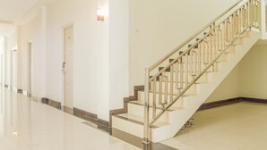 Een modern hotelinterieur met een gepolijste trap, een gang met deuren en een schone, betegelde vloer.