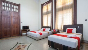 A hotel room with two beds, wooden wardrobe, and a television. - RedDoorz @ Lawang (Malang)
