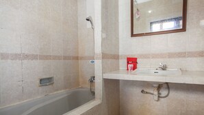 A bathroom with a bathtub, a sink, and a mirror. - RedDoorz @ Lawang (Malang)