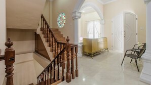 A grand staircase with wooden balusters, a stained glass window, and a reception area with a glass counter. - RedDoorz near Grand Palladium (Medan)