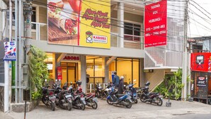 Un edificio con publicidad de KABOBS, un cartel de HUBUNGI y varias motocicletas estacionadas.