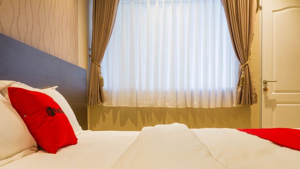 Una habitación de hotel con una cama, una ventana con cortinas y una puerta.