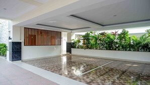 A spacious lobby with a checkered floor, a wooden slat partition, and a row of green plants. - Urbanview Hotel Syariah Casa Azmya Yogyakarta (Depok)