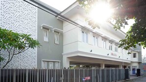 A two-story building with a gated entrance and a covered parking area. - Urbanview Hotel Syariah Casa Azmya Yogyakarta (Depok)