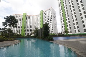 Un hotel moderno con zona de piscina, rodeado de edificios altos y palmeras.