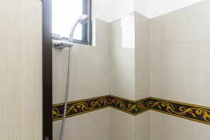 A corner of a bathroom with a shower, a decorative black and yellow border, and a window. - RedDoorz near RSU Suaka Insan (Banjarmasin)