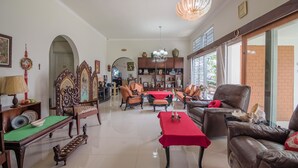 A spacious living room with a high ceiling, a chandelier, and a large window. - RedDoorz Syariah Plus @ Banjarbaru (Banjarbaru)