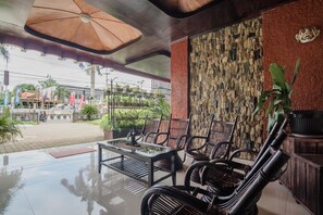 Un grand espace extérieur aménagé avec un mur en pierre, une table en bois et des chaises en osier.