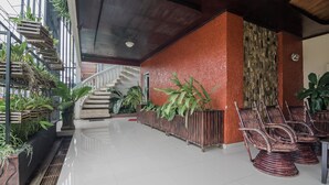 A spacious lobby with a staircase, potted plants, and wicker chairs. - RedDoorz Syariah Plus @ Banjarbaru (Banjarbaru)