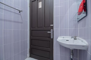 A bathroom with a dark door, a white sink, and a red towel hanging on a rack. - RedDoorz Syariah Plus @ Banjarbaru (Banjarbaru)