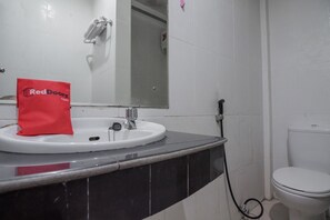 Une salle de bain avec un lavabo blanc, un plan de toilette noir et des toilettes.