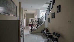 Ein geräumiger Flur mit Treppe, Essbereich und einer Bank mit Blumen.