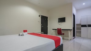 Ein Hotelzimmer mit einem Bett, einem Schreibtisch, einem Sessel, einem Fernseher und einem Kleiderschrank.