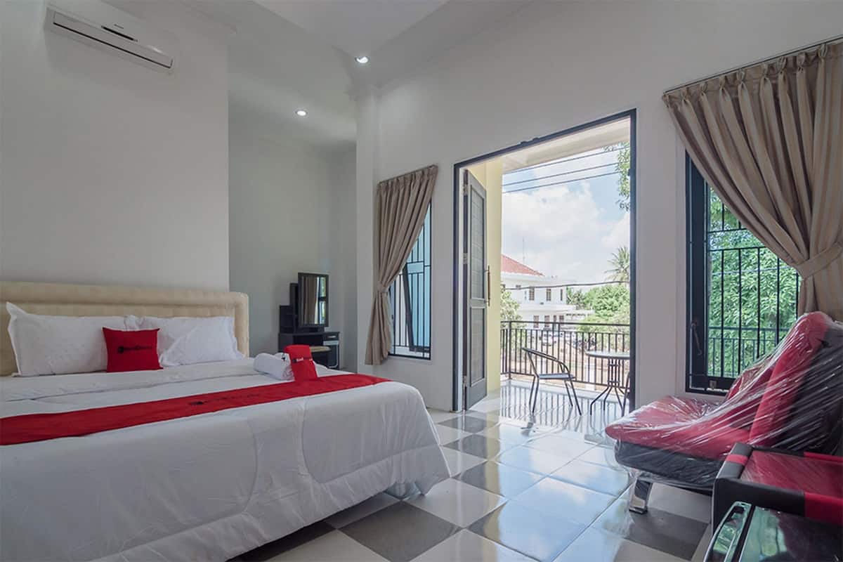 Une chambre d’hôtel avec un lit, une télévision, un balcon avec une table et des chaises, et une vue sur l’extérieur.
