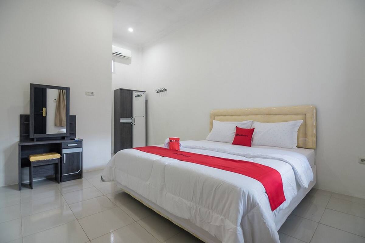 Une chambre d’hôtel avec un lit, un bureau, une armoire et un miroir.
