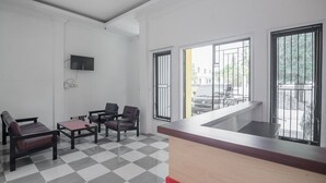 A reception area with a checkered floor, a reception desk, and two chairs. - RedDoorz near Sultan Thaha Airport Jambi (Jambi)