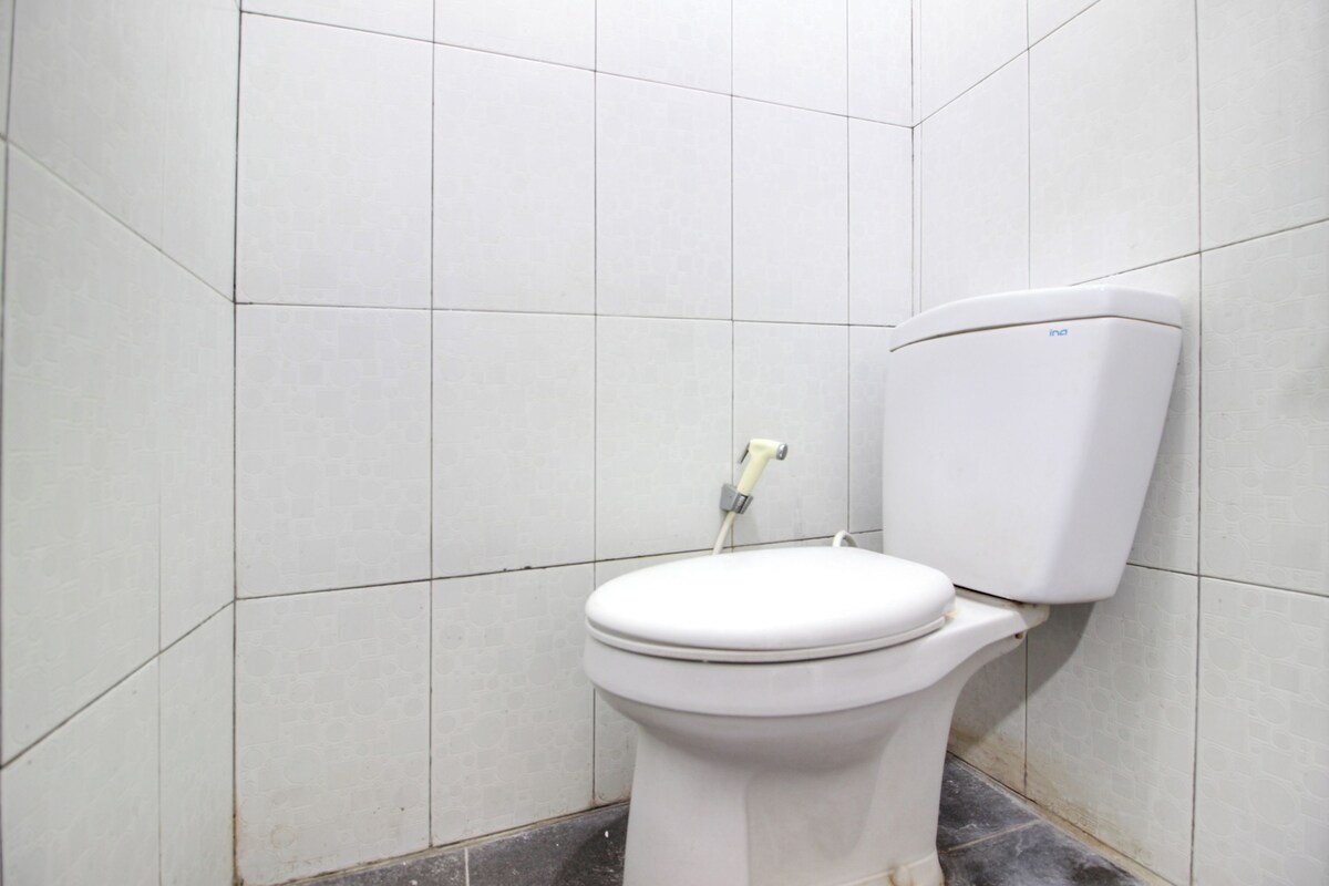 Eine weiße Toilette in einem Badezimmer mit gefliesten Wänden und einem gefliesten Boden.