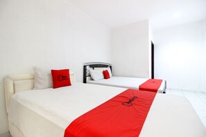 A hotel room with two beds, each with a red and white bedspread, and a white headboard. - RedDoorz near RS Sarjito Yogyakarta 2 (Depok)