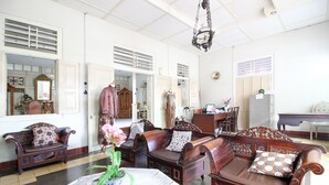 A spacious room with a large wooden sofa set, a dining table, and a decorative vase with flowers. - RedDoorz Syariah near Wijilan Yogyakarta (Yogyakarta)