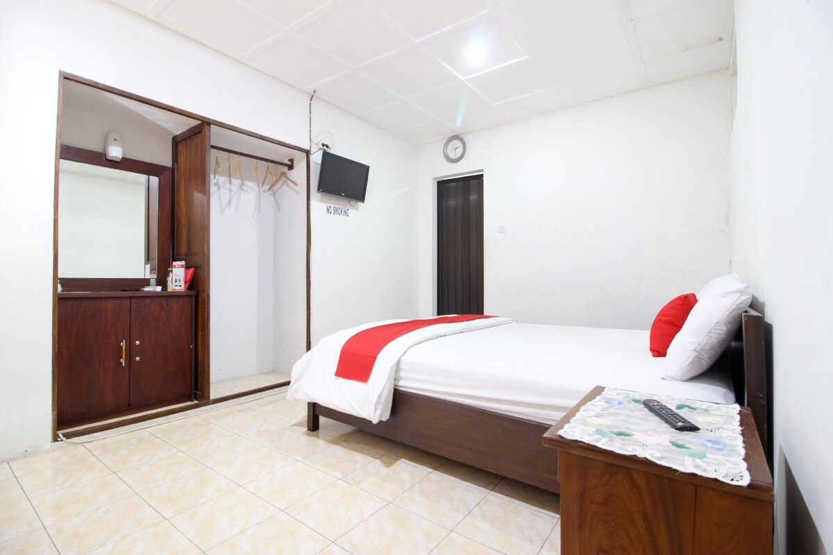 Une chambre à coucher avec un lit, une télévision, une armoire et une table de chevet.