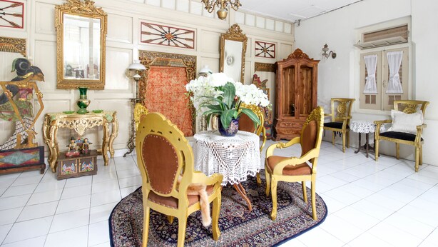 A room with a dining table, chairs, a chandelier, and ornate decorations. - RedDoorz Syariah near Wijilan Yogyakarta (Yogyakarta)