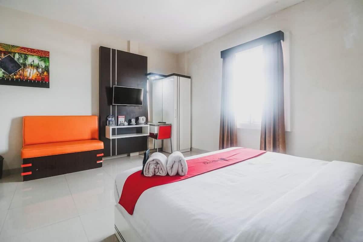 A hotel room with a bed, a desk, a television, and a window with curtains.