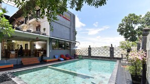 Ein Swimmingpool mit Liegestühlen, einer Bar und einem Gebäude mit der Aufschrift 'BALI Residence'.