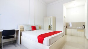 A hotel room with a bed, a desk, a chair, a wardrobe, and a bathroom. - RedDoorz Syariah @ Griya Izzara Guest House (Yogyakarta)