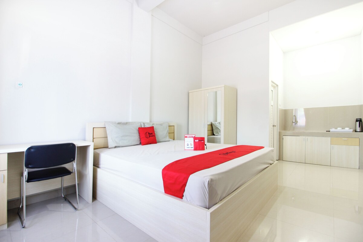 A hotel room with a bed, a desk, a chair, a wardrobe, and a bathroom.