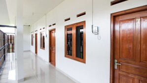 A corridor with wooden doors, a phone, and a metal railing. - RedDoorz Syariah @ Griya Izzara Guest House (Yogyakarta)