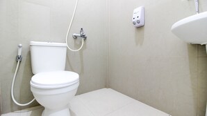A bathroom with a toilet, a handheld showerhead, and a wall-mounted soap dispenser. - RedDoorz Syariah @ Griya Izzara Guest House (Yogyakarta)