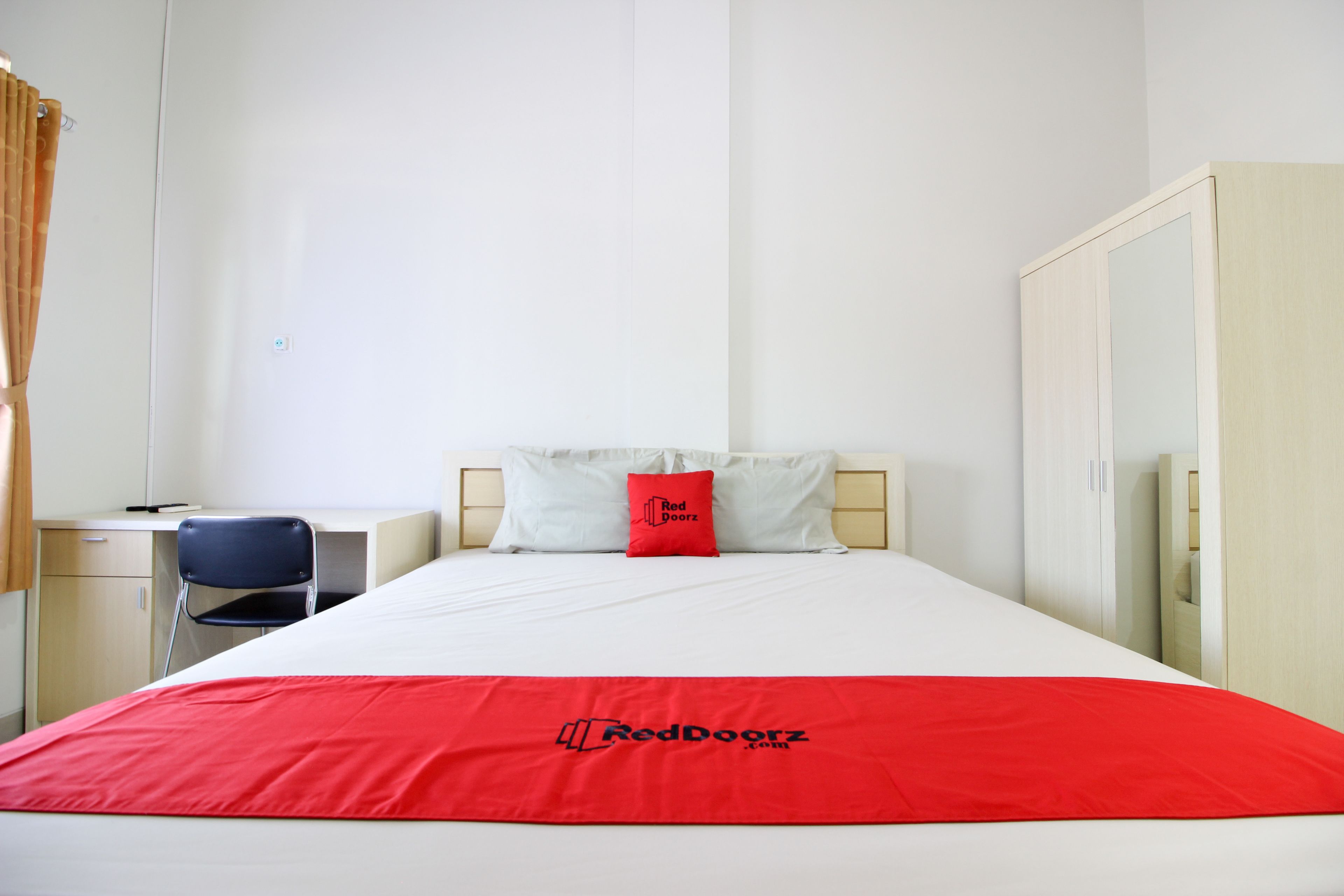A hotel room with a bed, a desk, a chair, and a wardrobe.