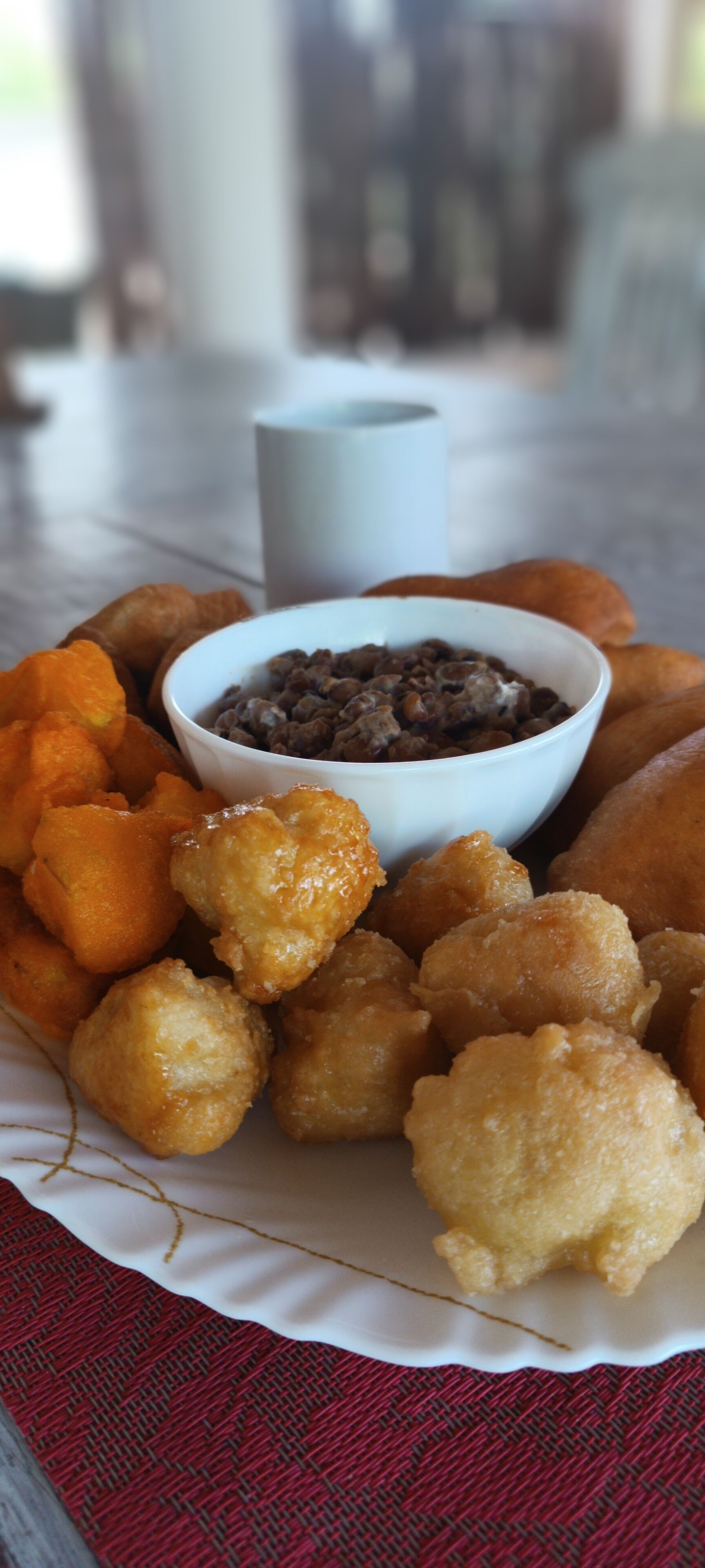 A plate of fried dough balls with a bowl of chocolate sauce.
