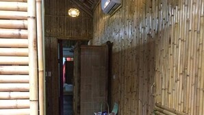 Een corridor met bamboe wanden, een koelkast en een plank vol witte pantoffels.
