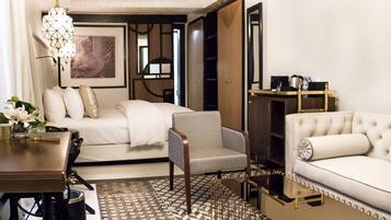 Habitación de hotel moderna con cama, sofá, sillón, escritorio y mesa de centro.