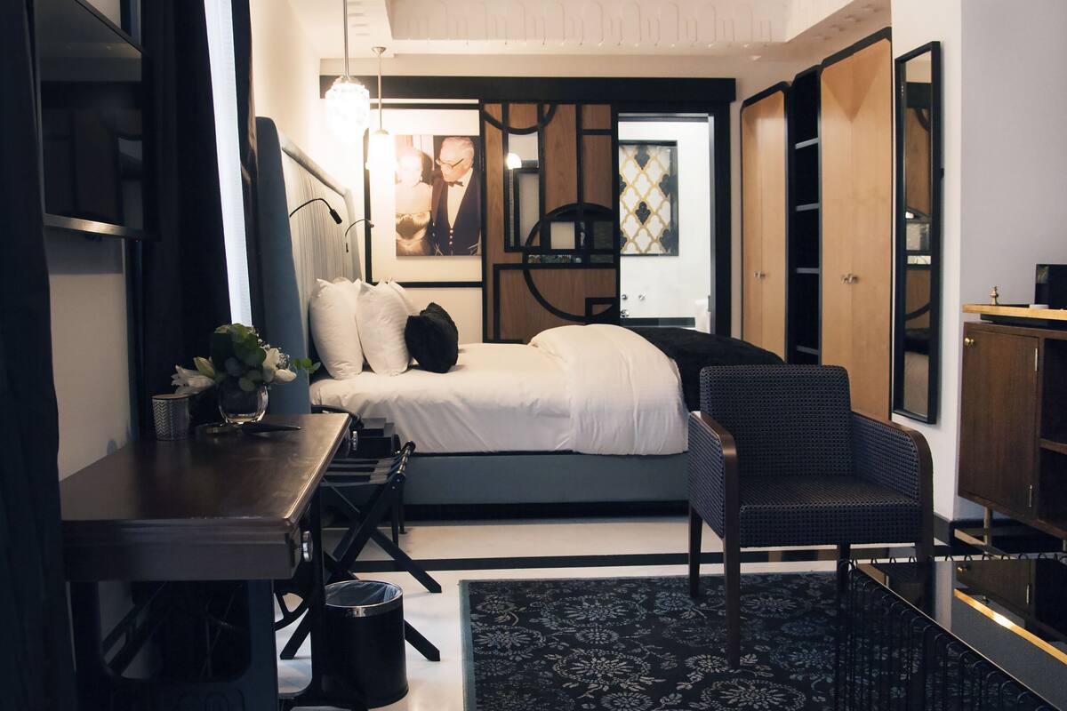 A compact bedroom with a bed, a desk, a chair, and a small table.