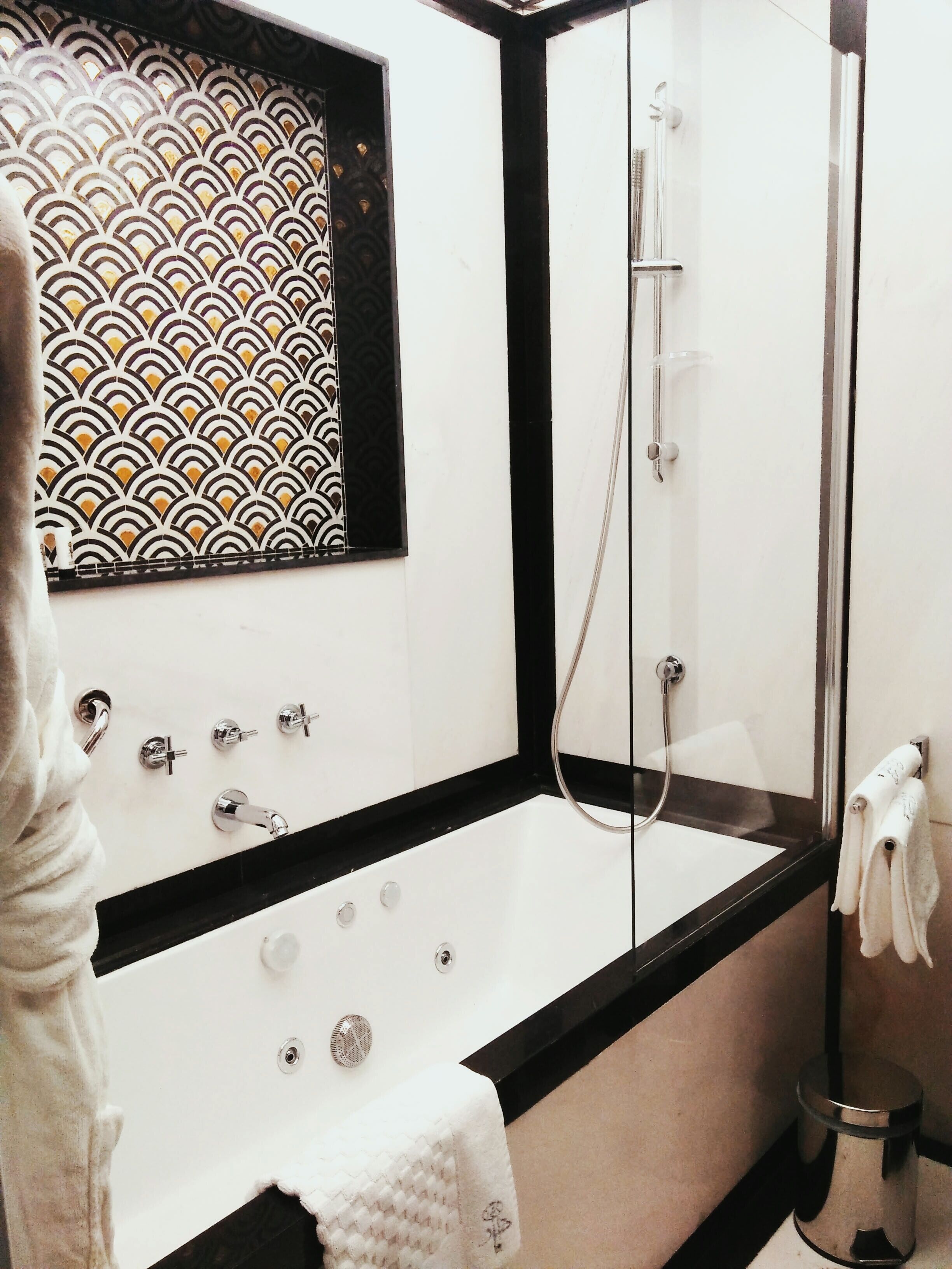 Un baño moderno con una bañera independiente, cabina de ducha y pared con diseño.