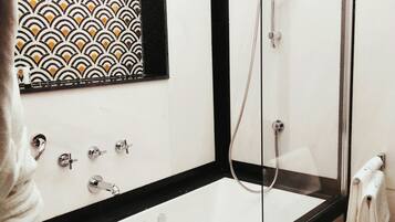 Un baño moderno con una bañera independiente, cabina de ducha y pared con diseño.
