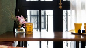 A table with a vase of flowers, a mug, and a tray with cups.