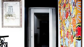 Un pasillo con suelo a cuadros blancos y negros, un mural colorido a la derecha y un cuadro enmarcado a la izquierda.