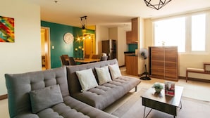 A modern living room with a sectional sofa, a dining area, and a kitchen. - RedDoorz Plus @ Kamuning Quezon City (Quezon City)