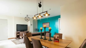 A dining area with a wooden table, six chairs, and a television in the background. - RedDoorz Plus @ Kamuning Quezon City (Quezon City)