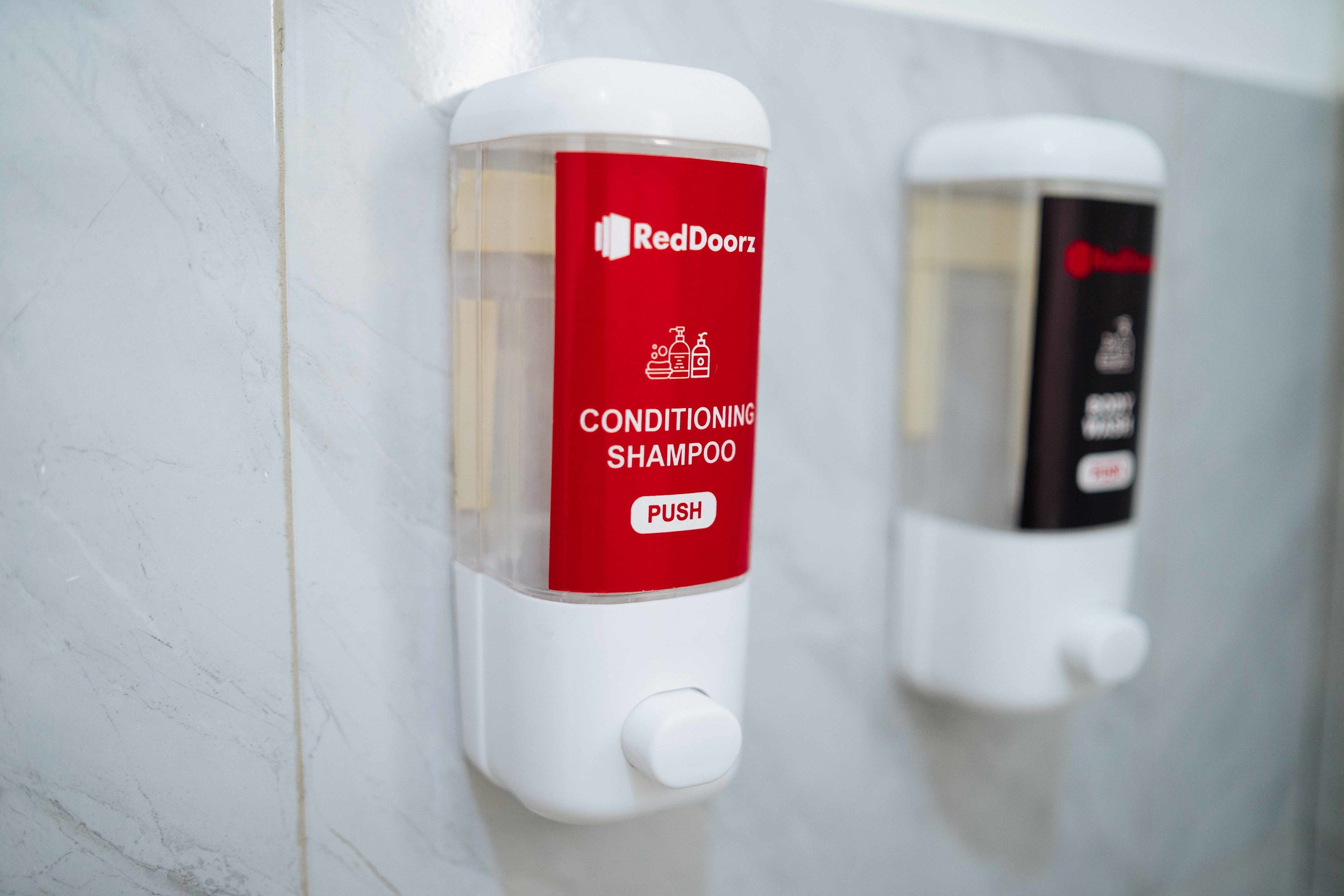 Un baño con dos dispensadores de desinfectante para manos, uno etiquetado como 'RedDoorz' y el otro 'RedDoorz'.
