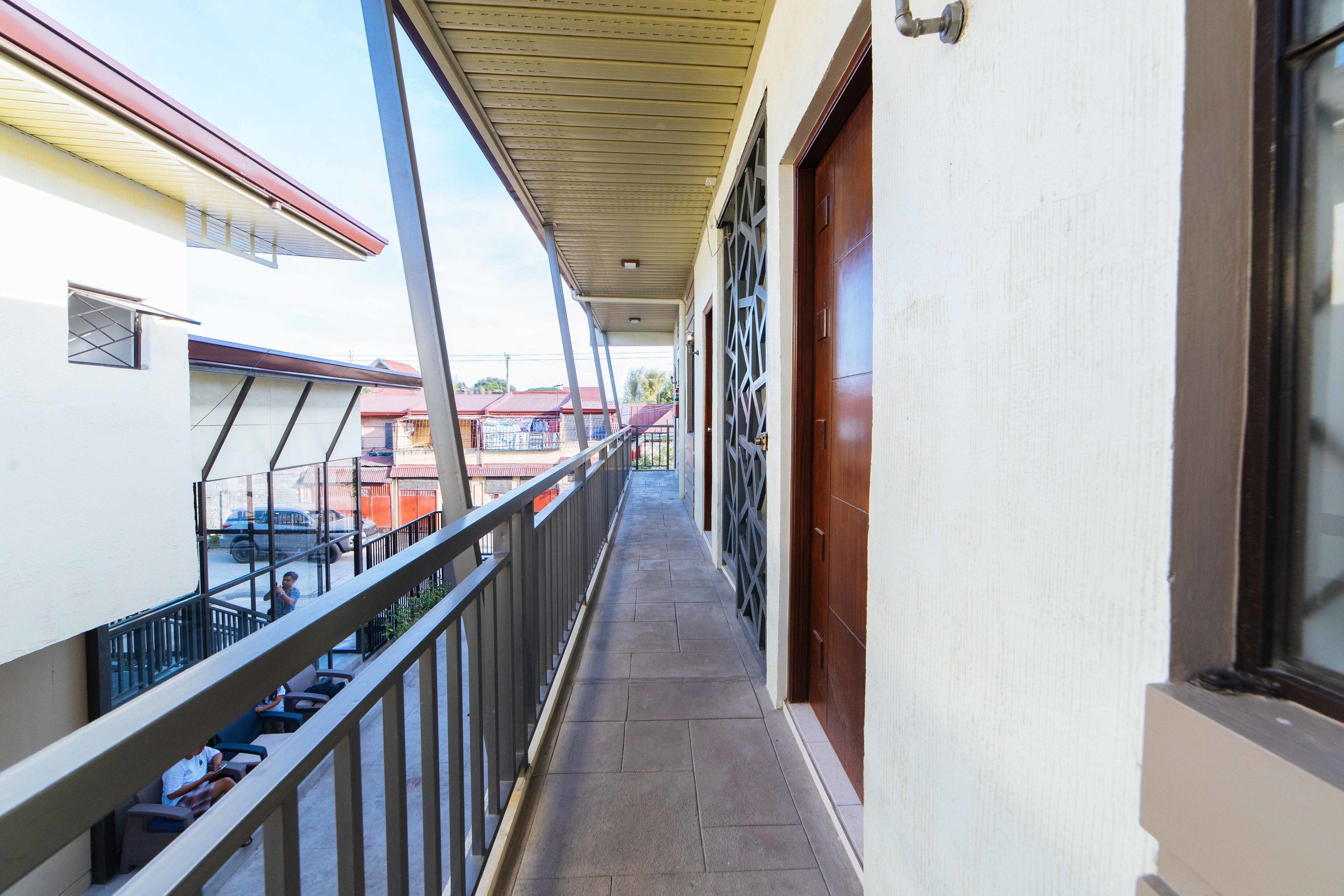 A covered balcony with a railing, a door, and a window.