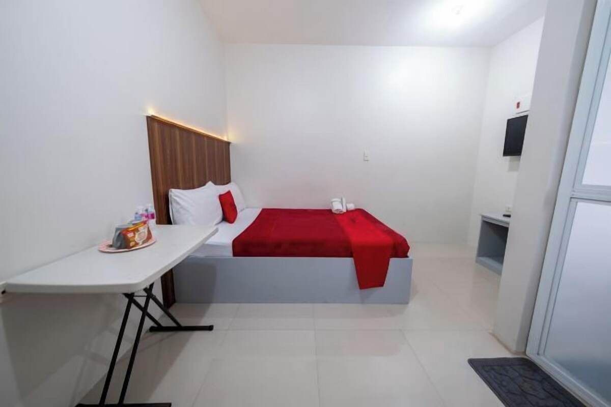 Une petite chambre comprenant un lit, une petite table et une table de chevet.